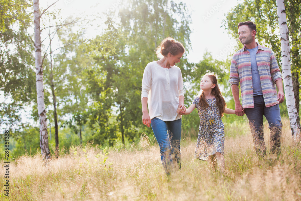 Fototapeta premium Loving young caucasian family walking across woods all holding hands