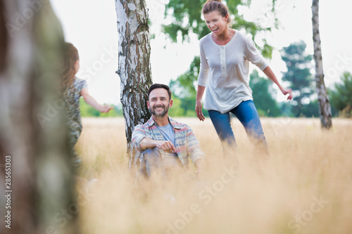 Loving mother plays with her daughter in the woods whilst her husband looks at the camera