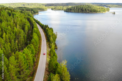 Aerial view of lake with island, road and forest on a summer sunny day in Finland. Drone photography