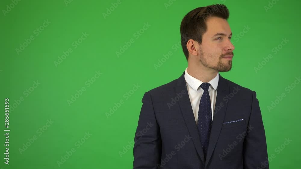 A young handsome businessman looks around with a proud smile - green screen studio A young handsome businessman looks around with a proud smile - green screen studio