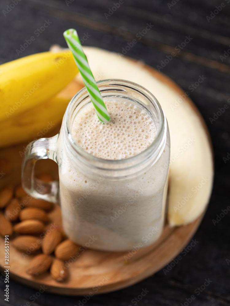 Fresh banana smoothie on a wooden table in a jar . With oatmeal and almonds