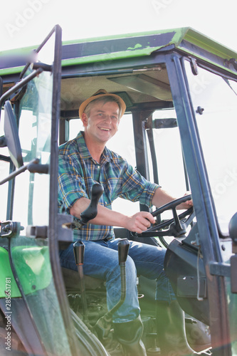 Smiling mature farmer driving tractor in field