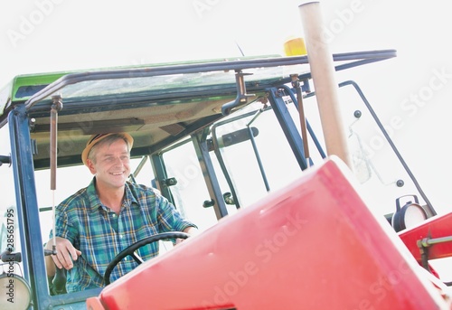 Smiling mature farmer driving tractor in field