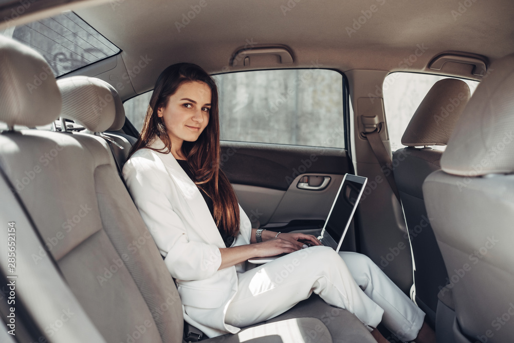 Fashion Stylish Girl in White Suit Works at Laptop in Car