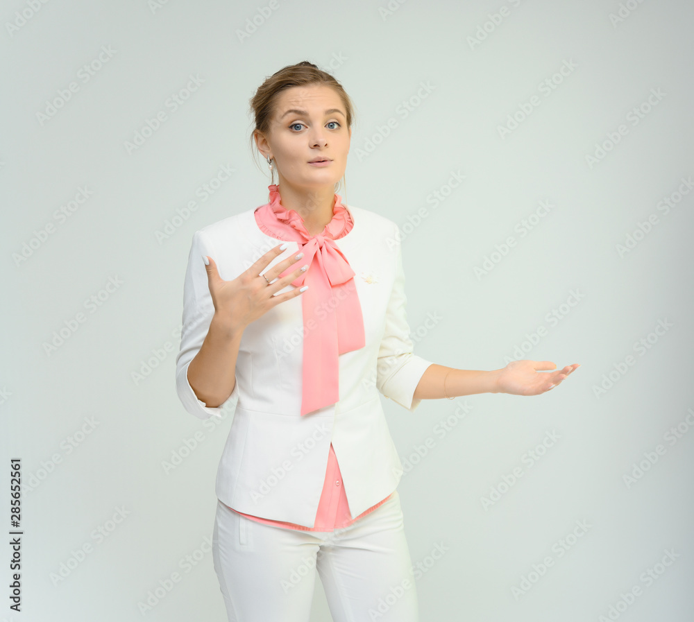 Photo studio portrait of a cute young woman girl in a beautiful suit of white-pink tender color on a white background. He stands right in front of the camera, explains with emotion. Photo studio portrait of a cute young woman girl in a beautiful suit of white-pink tender color on a white background. He stands right in front of the camera, explains with emotion.
