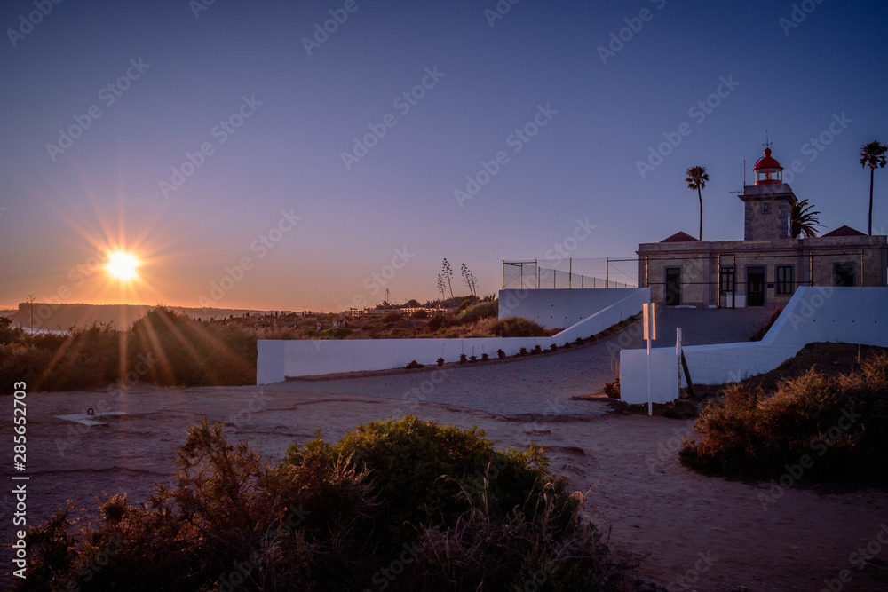 Landscape panorama with beautiful and colorful sunset, silhouettes in the mountains on the horizon and Ponta da Piedade Lighthouse, Lagos - Algarve PORTUGAL