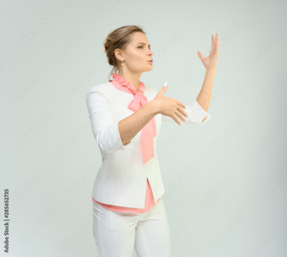Photo studio portrait of a cute young woman girl in a beautiful suit of white-pink tender color on a white background. He stands right in front of the camera, explains with emotion. Photo studio portrait of a cute young woman girl in a beautiful suit of white-pink tender color on a white background. He stands right in front of the camera, explains with emotion.