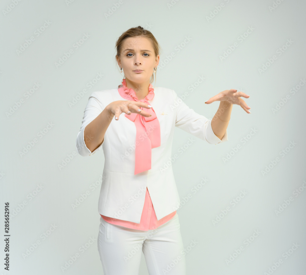 Photo studio portrait of a cute young woman girl in a beautiful suit of white-pink tender color on a white background. He stands right in front of the camera, explains with emotion. Photo studio portrait of a cute young woman girl in a beautiful suit of white-pink tender color on a white background. He stands right in front of the camera, explains with emotion.