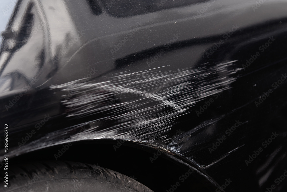Damaged car body after a crash accident. Black vehicle wheel arch closeup.  Scratches and dents. Repairs needed. Stock Photo