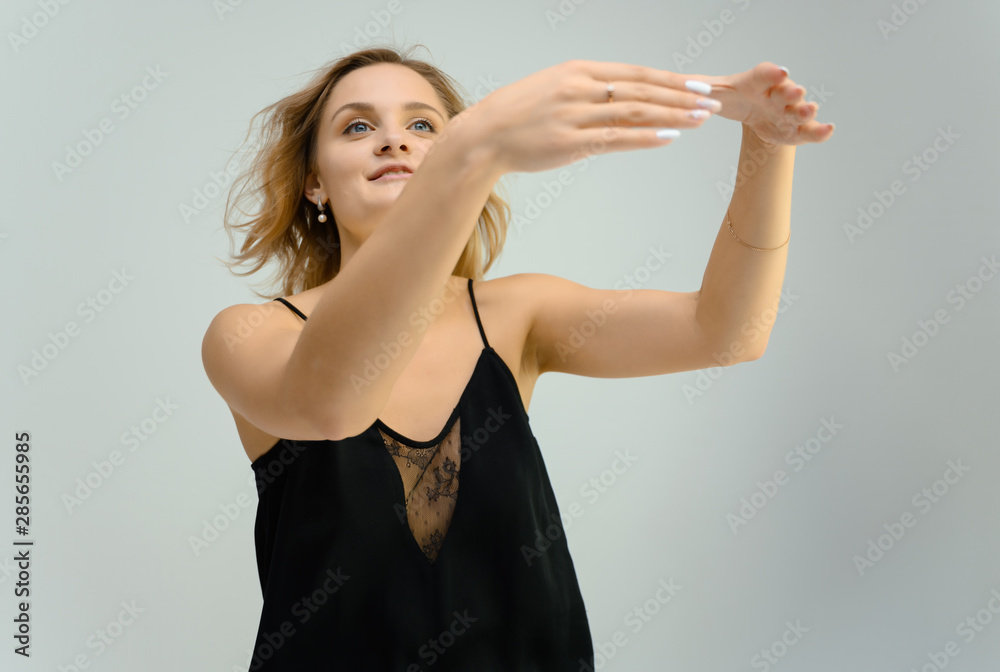 Photo studio portrait of a cute blonde young woman girl in a black blouse on a white background. He stands right in front of the camera, explains with emotion. Photo studio portrait of a cute blonde young woman girl in a black blouse on a white background. He stands right in front of the camera, explains with emotion.
