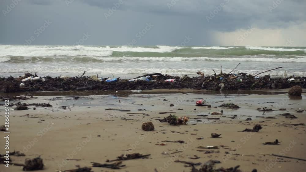 waves roll on littered after storm beach under overcast sky waves roll on littered after storm beach under overcast sky