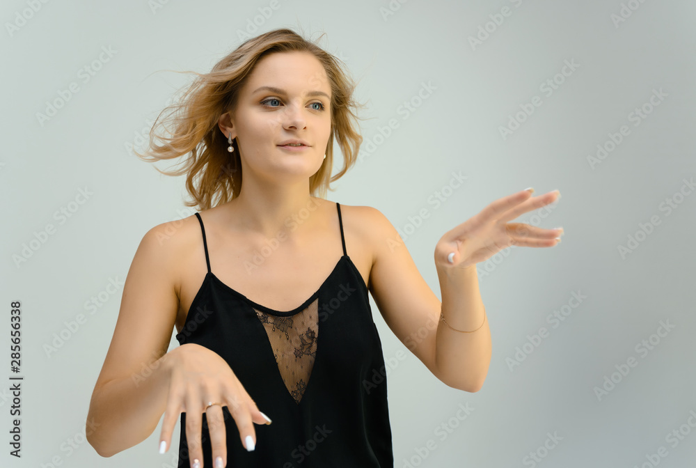 Photo studio portrait of a cute blonde young woman girl in a black blouse on a white background. He stands right in front of the camera, explains with emotion. Photo studio portrait of a cute blonde young woman girl in a black blouse on a white background. He stands right in front of the camera, explains with emotion.
