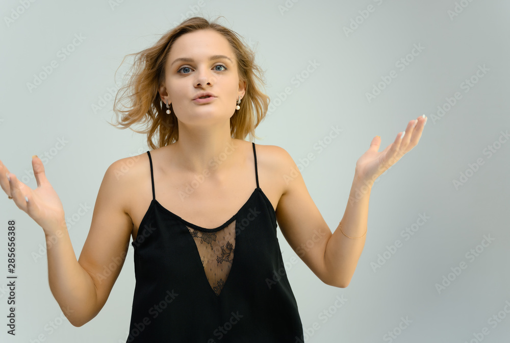 Photo studio portrait of a cute blonde young woman girl in a black blouse on a white background. He stands right in front of the camera, explains with emotion. Photo studio portrait of a cute blonde young woman girl in a black blouse on a white background. He stands right in front of the camera, explains with emotion.