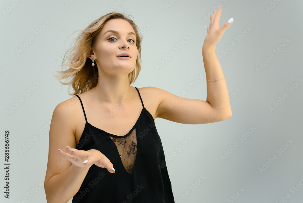 Photo studio portrait of a cute blonde young woman girl in a black blouse on a white background. He stands right in front of the camera, explains with emotion. Photo studio portrait of a cute blonde young woman girl in a black blouse on a white background. He stands right in front of the camera, explains with emotion.