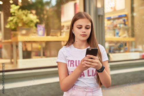 teen girl with a phone near a shop window