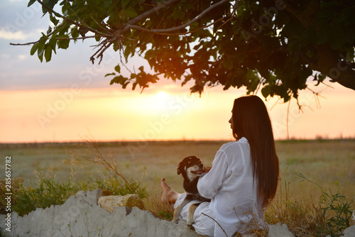 girl in white clothes with a dog at sunset
