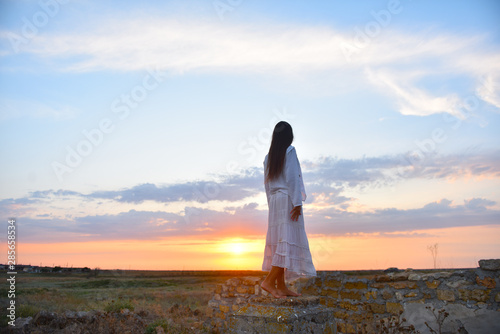 girl in white clothes at sunset on the ruined wall