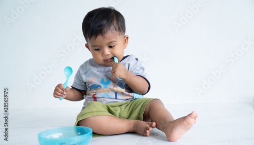 Cute little asin baby boy with spoon