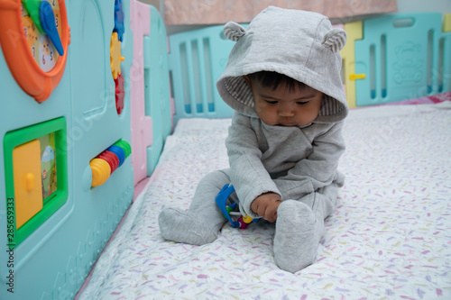 Cute little asin baby boy sitting and play toy in room photo