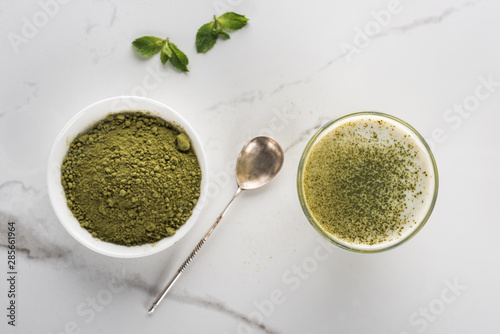top view of matcha tea powder and drink in glass on white table