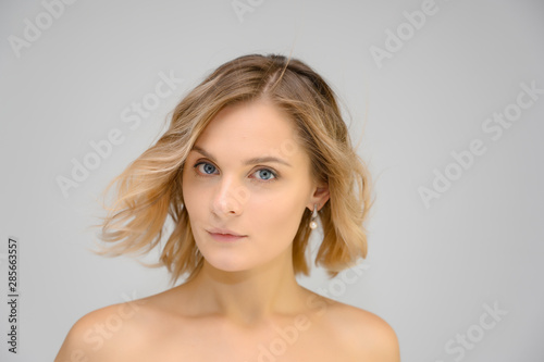 Closeup photo studio portrait of a fashionable pretty blonde young woman girl with beautiful hair on a white background. Standing right in front of the camera. Beauty  cosmetics.