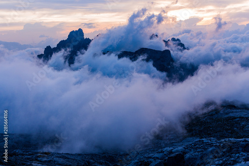 Stunning sunset over mountain alpine landscape and high summits or peak of Gosaukamm ridge, Dachstein. Sunset or sunrise colors in Alps, low clouds, motion blurr. Dreamy landscape.