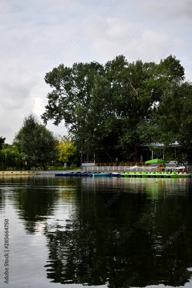 Moscow, Russia - August 21, 2019: Pond in the Gorky Park with boat rental station and a cafe in the background on a cloudy summer day