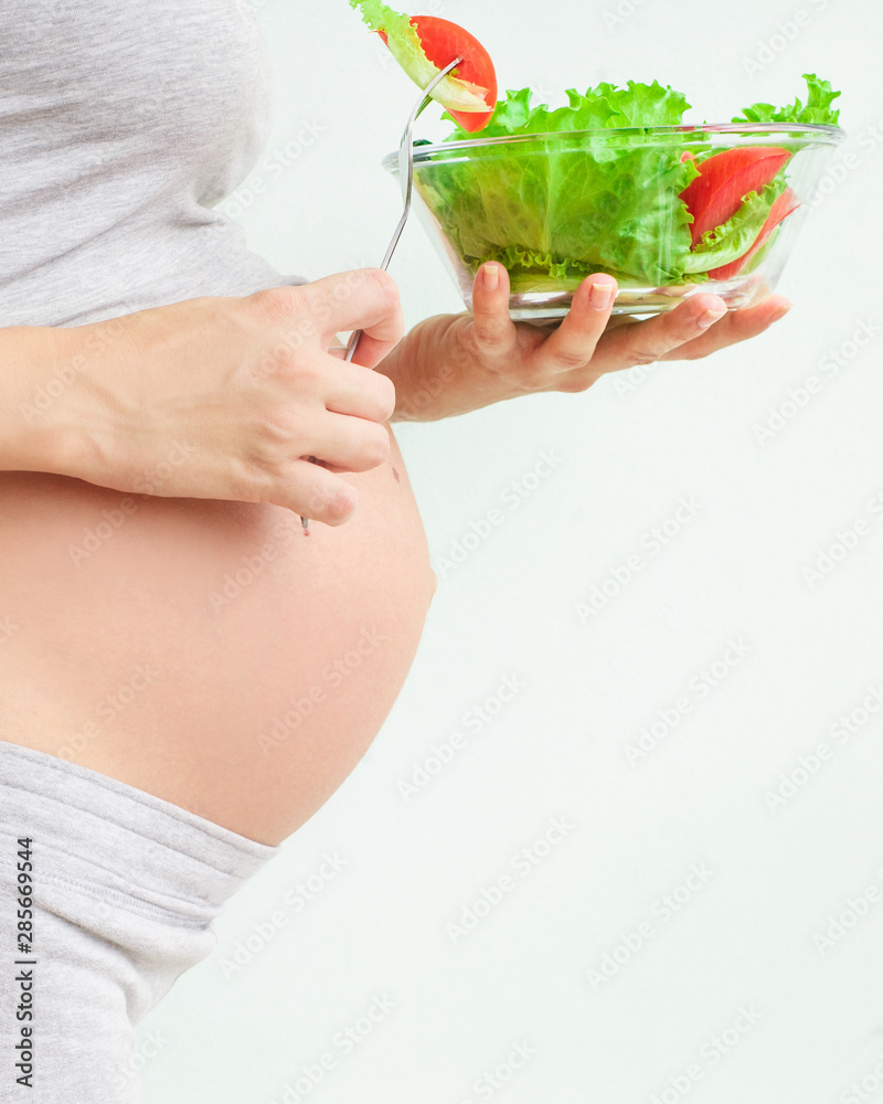 healthy nutrition and pregnancy. pregnant woman's belly and vegetable salad. Pregnancy Nutrition
