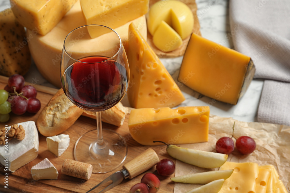 Board with different kinds of delicious cheese, snacks and wine on marble table Board with different kinds of delicious cheese, snacks and wine on marble table