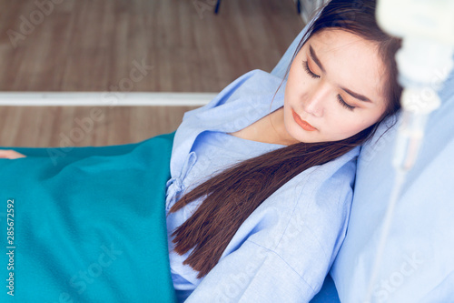 Asian young female patients wearing blue shirts lying in the bed with a bright face Have better symptoms while waiting for the doctor to check