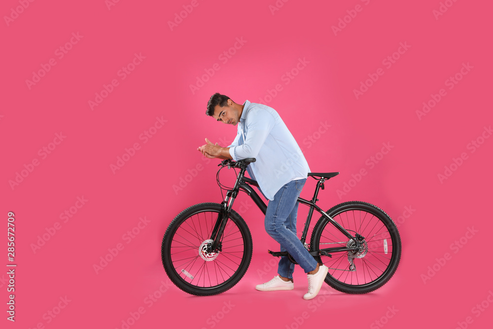 Handsome young man with modern bicycle on pink background Handsome young man with modern bicycle on pink background