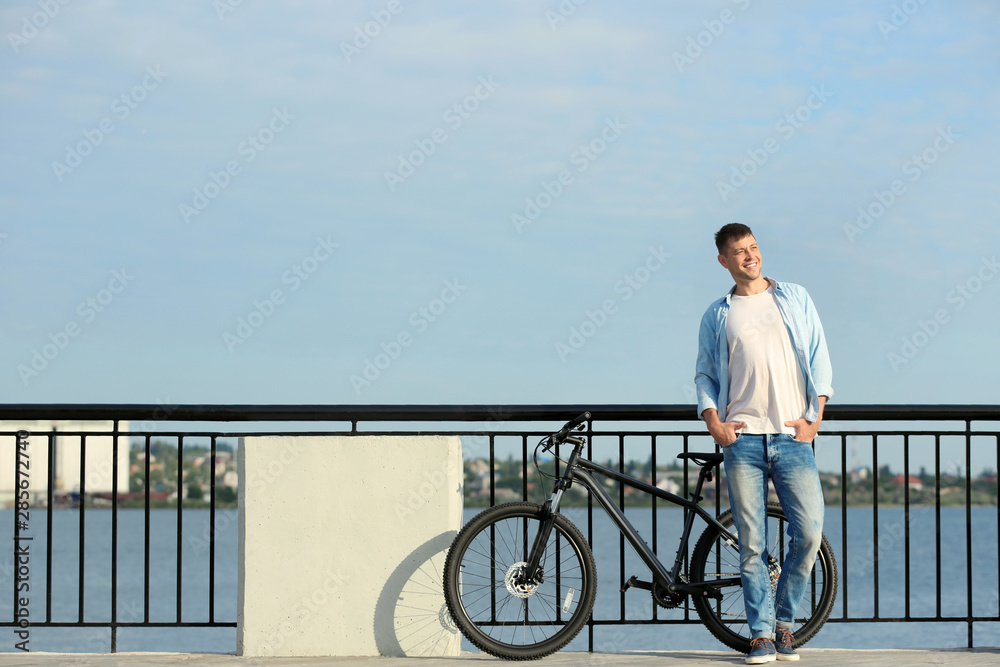 Handsome man with modern bicycle near river Handsome man with modern bicycle near river