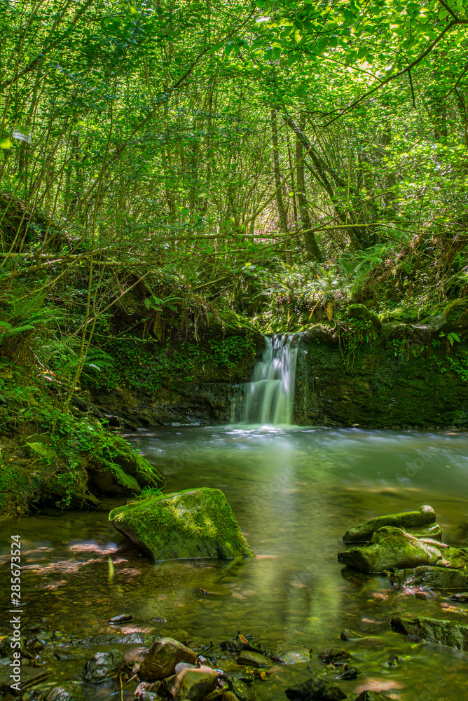 Sun ray lights over a small waterfall in a river in Galdames, Basque Country, Spain Sun ray lights over a small waterfall in a river in Galdames, Basque Country, Spain