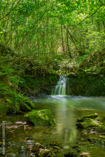 Sun ray lights over a small waterfall in a river in Galdames, Basque Country, Spain