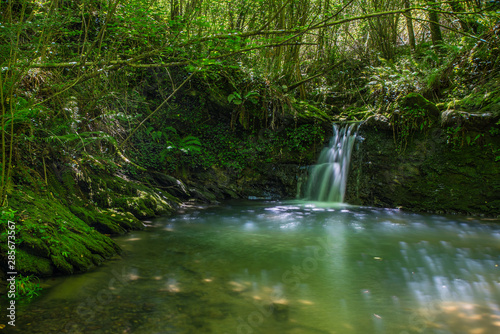 Sun ray lights over a small waterfall in a river in Galdames, Basque Country, Spain
