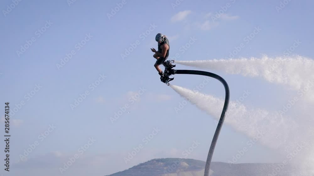 Flyboarding is a new extreme water sport. Athletic man performs tricks in flight. Spectacular sports coups and turns.