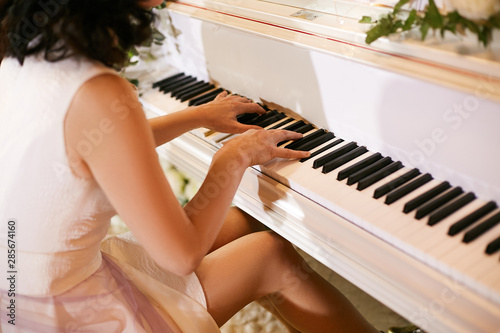 Fotografie, Obraz Girl pianist plays the white piano during a wedding celebration.