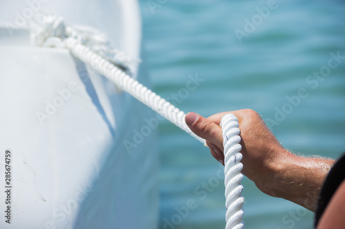 men's hands tied the rope on the yacht photo