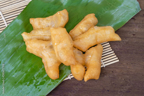 doughstick on banana leaves on a wooden background photo