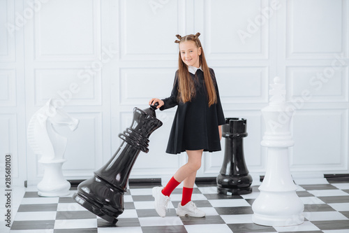 Emotional portrait of girl with chessboard. Funny child holding a game of chess in his arms while laughing. Cute smart kid, isolated on white background.