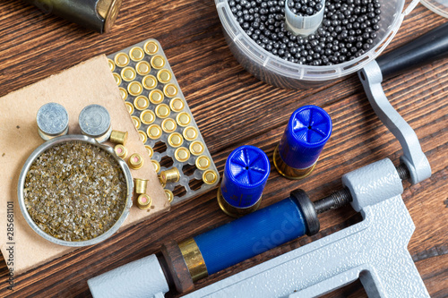 Shotgun shells reloading process with special reload equipment. Powder, bullets, fraction, shells, buckshot on the wooden background.