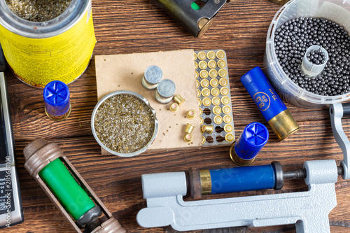 Shotgun shells reloading process with special reload equipment. Powder, bullets, fraction, shells, buckshot on the wooden background. photo