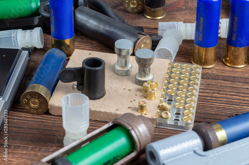 Shotgun shells reloading process with special reload equipment. Powder, bullets, fraction, shells, buckshot on the wooden background. photo