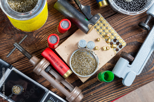 Shotgun shells reloading process with special reload equipment. Powder, bullets, fraction, shells, buckshot on the wooden background. photo