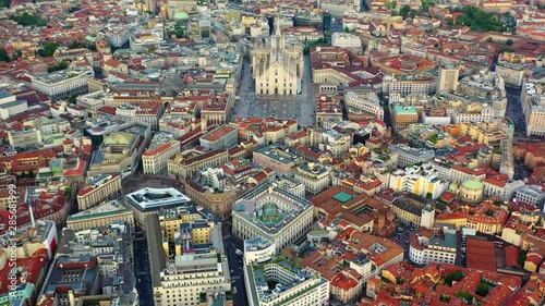 Aerial, reverse, drone shot, tilting away over the Milan Cathedral, Duomo di Milano, over buildings and architecture, on a sunny evening, in Lombardy, Italy photo