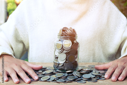 Scattered coins in the wooden backgroundpiggy bank, Hands of business, Concept of saving money for future. photo