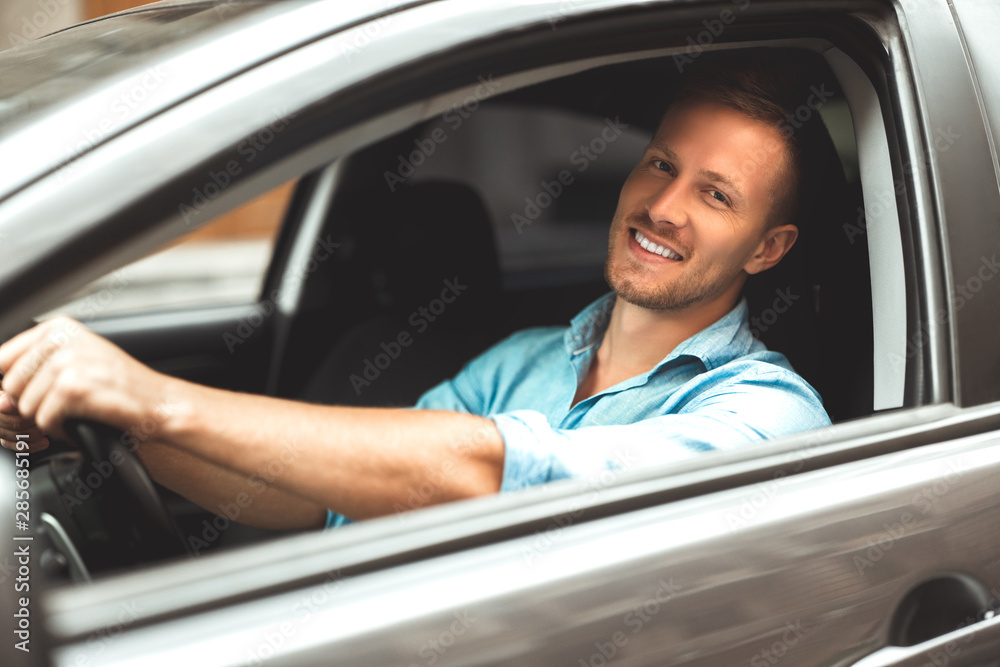 young handsome smiling man driving car close up