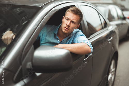 young handsome man driving his car looking nervous stuck in traffic jam