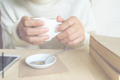 Relaxing moments , Cup of coffee and a book on wooden table in nature background, color of vintage tone and soft focus, winter morning concept.