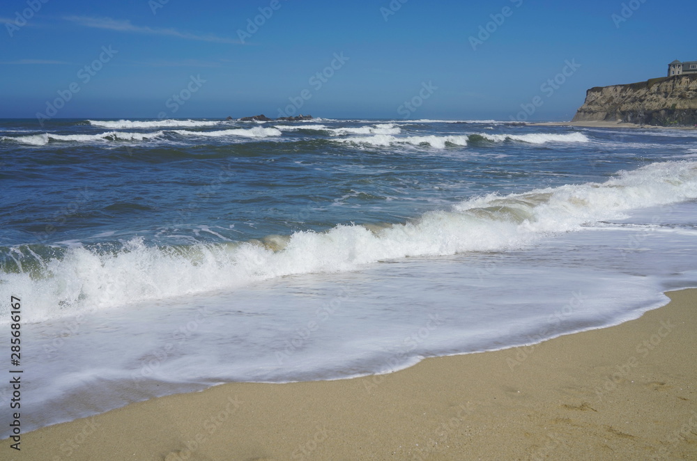Blue sky, white ocean waves and sunshine sandy beach at Pacific Coast, California